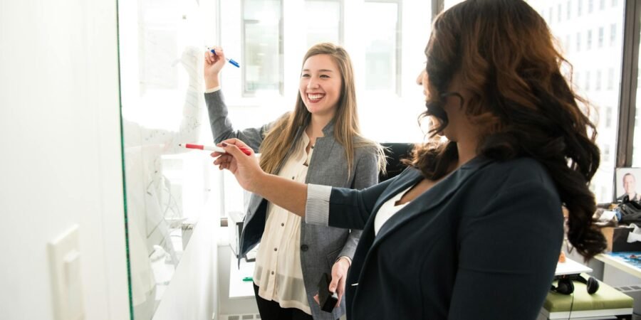 two women in front of dry erase board